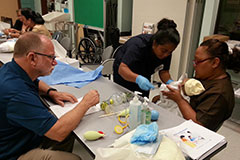Dr. James Finch, a nursing instructor at the University of Guam, looks on as Jessica Kerman, an emergency room nurse from Pohnpei State Hospital, performs a procedure during a training session on helping newborns to breathe. 