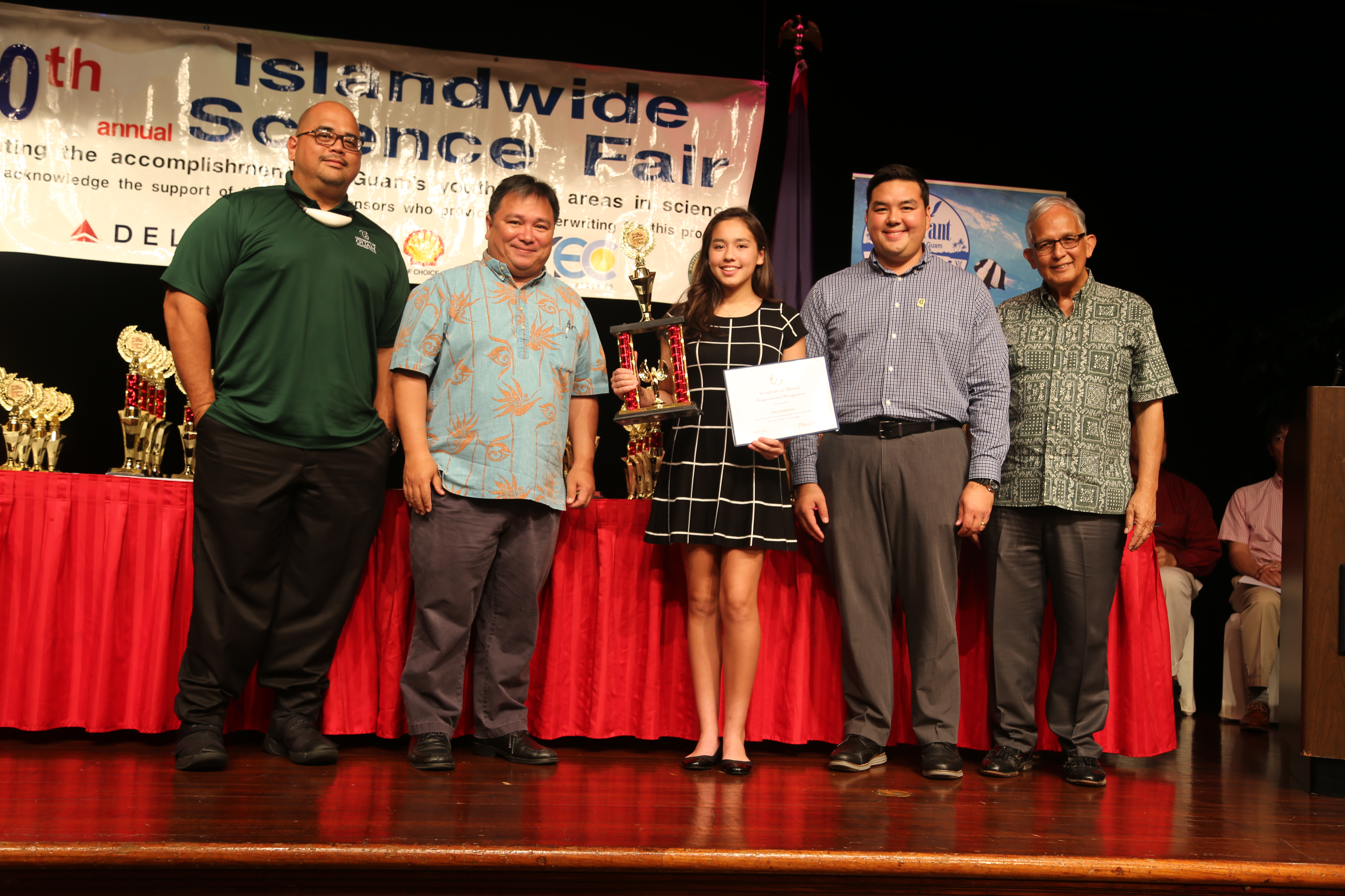 Talia Kriegal of St. John’s School (centered) receives the award for first place in Division 3. (From left to right) UOG Reference and Instruction Librarian, Roland San Nicolas, UOG Associate Professor of Biology Dr. Frank Camacho, Talia Kriegal, UOG Assistant Professor of Extension & Outreach Dr. Austin Shelton, and UOG President Dr. Robert Underwood.