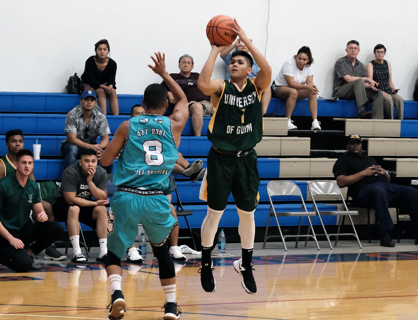 A.J. Carlos takes a shot against the Bulldogs in the previous UOG game as UOG President Thomas W. Krise and his wife, Patricia, watch in background.