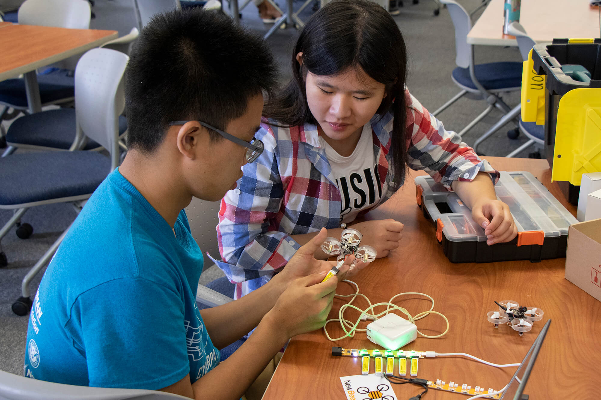 Yvan Chu, left, and Shaoying Zheng, right, attach a battery to the Tiny Whoop aircraft.