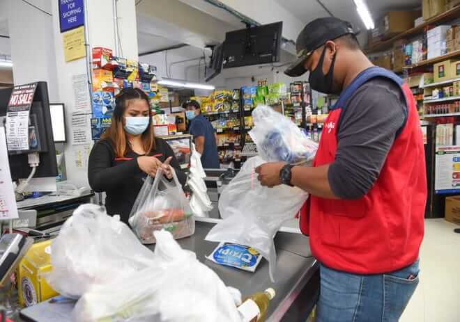 Employees bag groceries at Super Happy Mart in Barrigada.