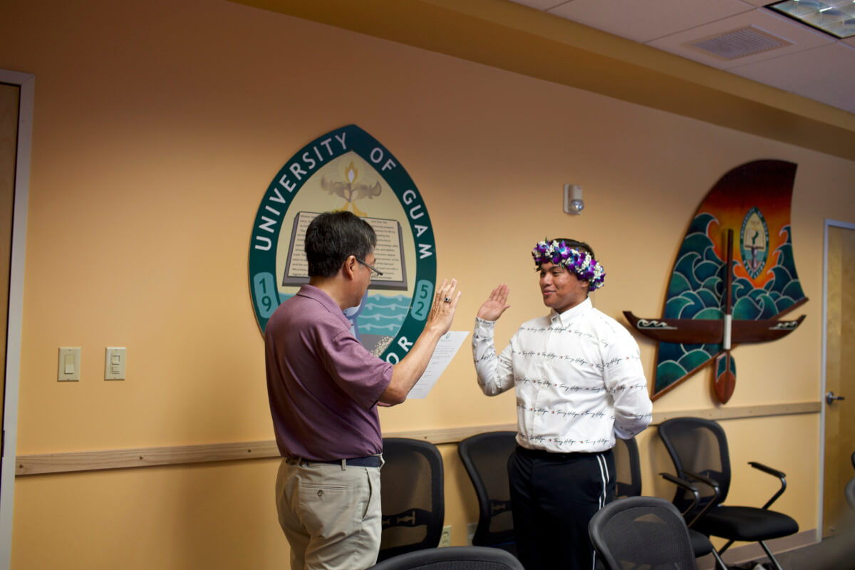 Regent Elvin Y. Chiang conducts the swearing in of Senior Mebric Navisaga. 