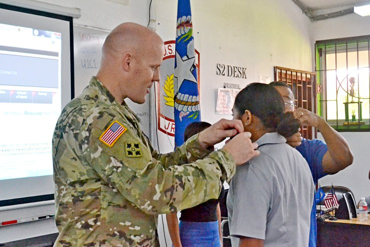 LTC Anderson and 1SG Jose King (Ret.) pin the PVT rank on Cadet Isa Reyes.