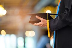 Photo of a graduating person holding a graduation cap