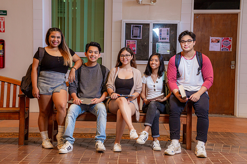 Photo of UOG students sitting on a bench on campus