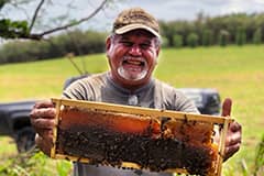 Photo of Guam beekeeper Mike Aguon holding a honeycomb