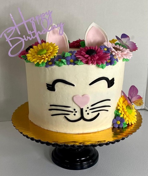 Bake Their Day cake simple round cake design with flowers and a cute smiling cat face with ears. 