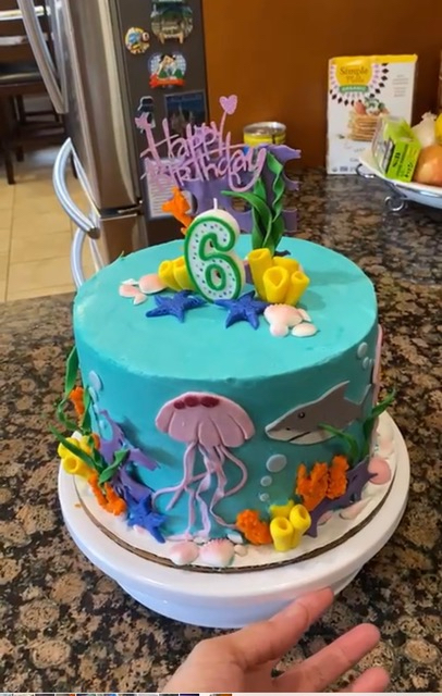 An ocean themed birthday cake with various underwater animals and plants around the sides and top,