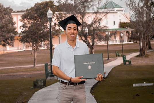 UOG student poses outdoors with Bachelor’s Degree