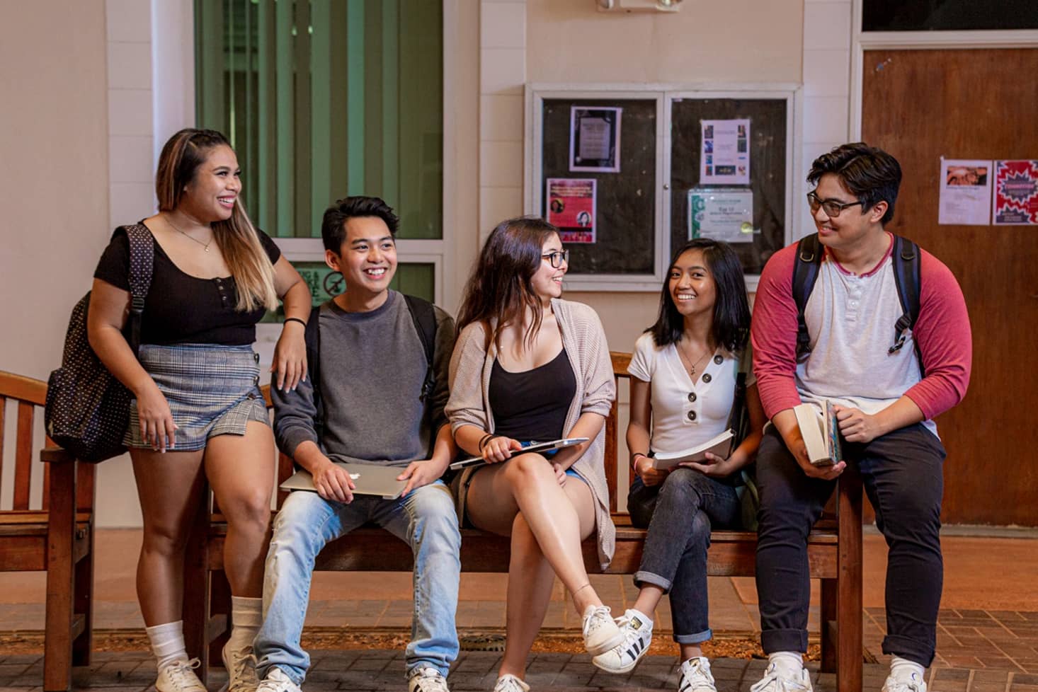 Students gather on a bench in HSS smiling and talking