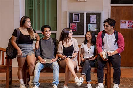 Students gather on a bench in HSS smiling and talking