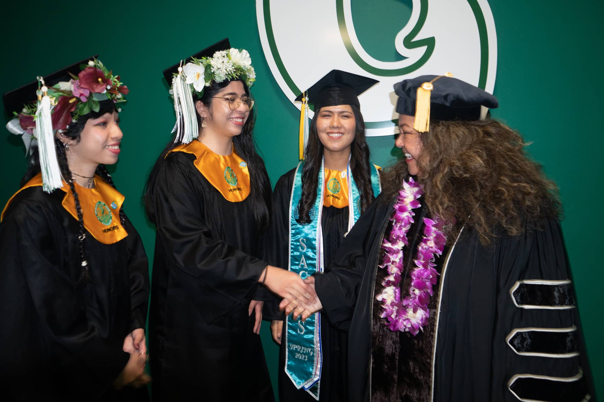 Fleurdeliza de Peralta shaking hands with the three valedictorians