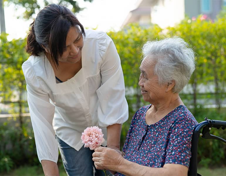 A caregiver supports an elderly woman