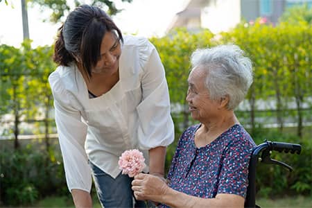 A caregiver supports an elderly woman 