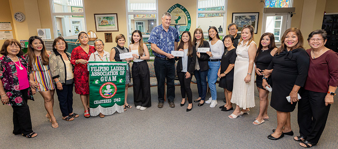 The Filipino Ladies Association of Guam (FLAG) recently awarded scholarships to three University of Guam students. FLAG representatives recently visited the University of Guam to award the scholarships to Veronica Marie Manicsic, sixth from left; Ansherina Borja, ninth from left; and Ella Pobre, 11th from left. Randy Wiegand, Vice President of Administration and Finance and Chief Business Officer, seventh from left, and Mark A. Duarte, Director of the Financial Aid and One Stop Office, back, join FLAG members.
