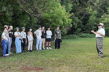 Photo of teacher lecturing to students outdoors