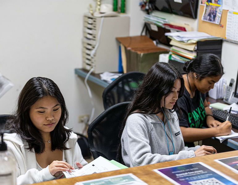 Three young interns help with paperwork in an office