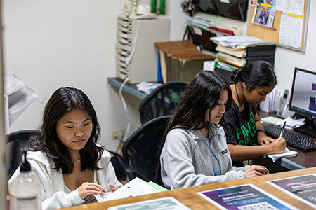 Three young interns help with paperwork in an office