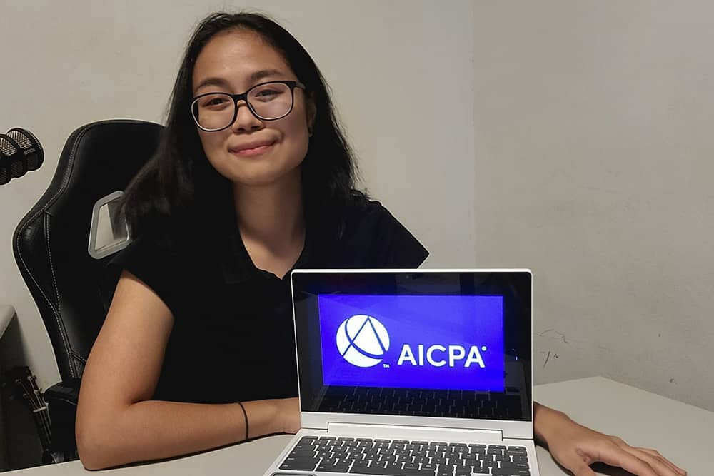 Jamabeva Masangkay poses for a photo with AICPA photo on laptop