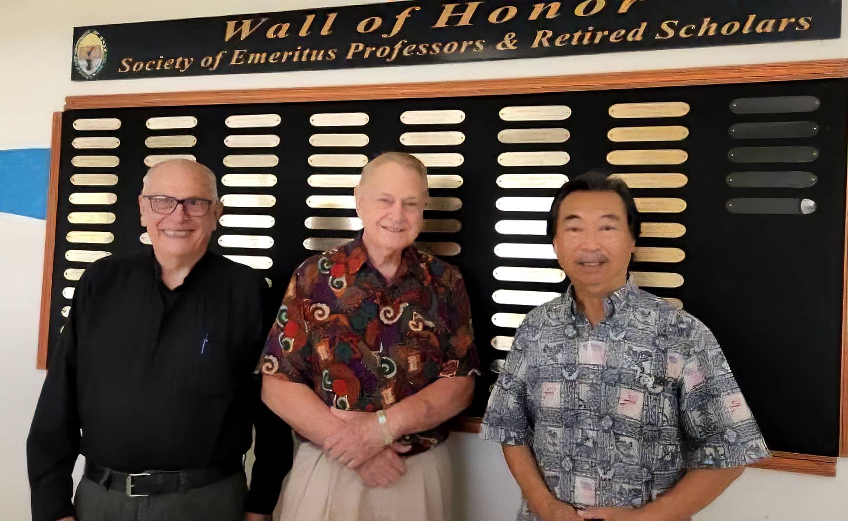 Three men, members of the SEPRS council, pose in front of the Emeritus Hall Wall of Honor.