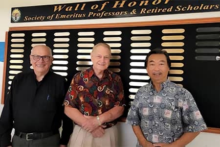 Three men, members of the SEPRS council, pose in front of the Emeritus Hall Wall of Honor.