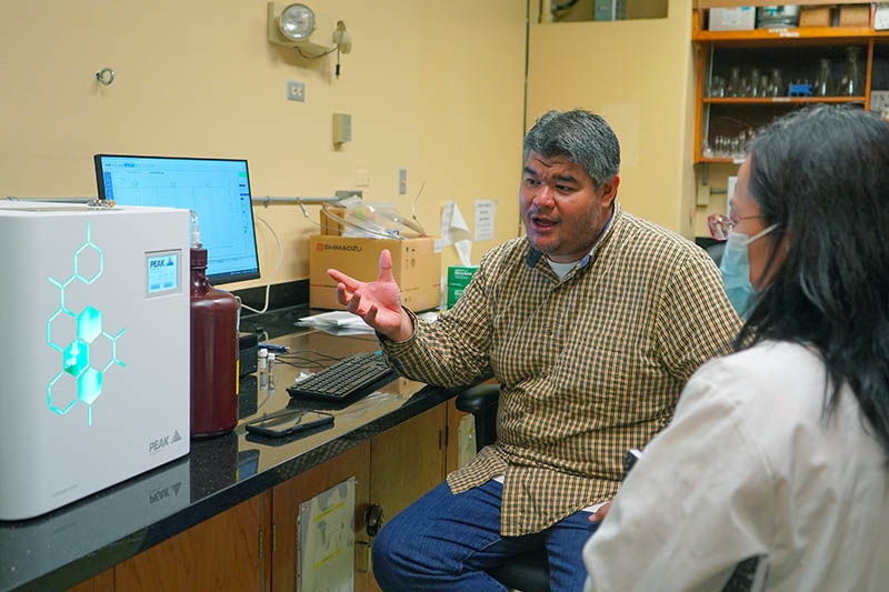 Photo of Dr. John Limtiaco and the GC-MS instrument