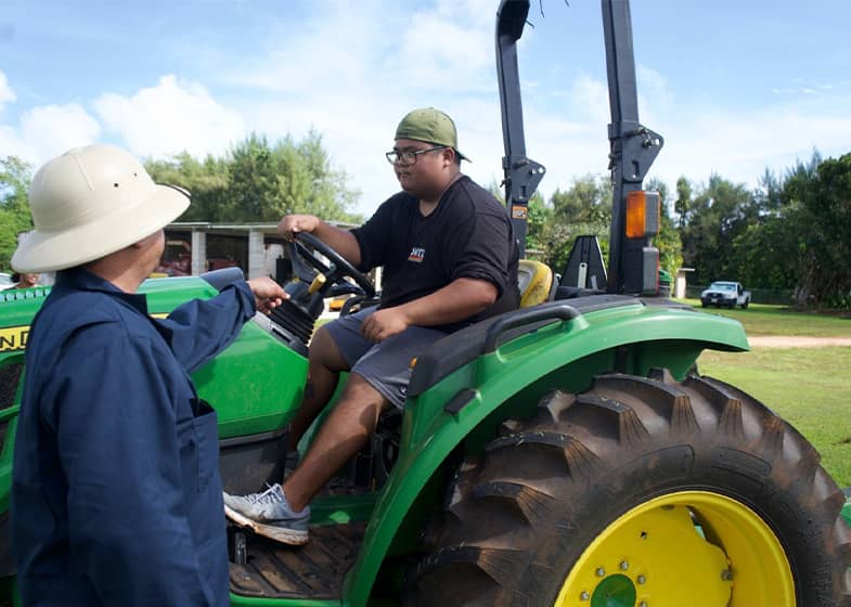 agricultural research technician teaches UOG student how to drive tractor
