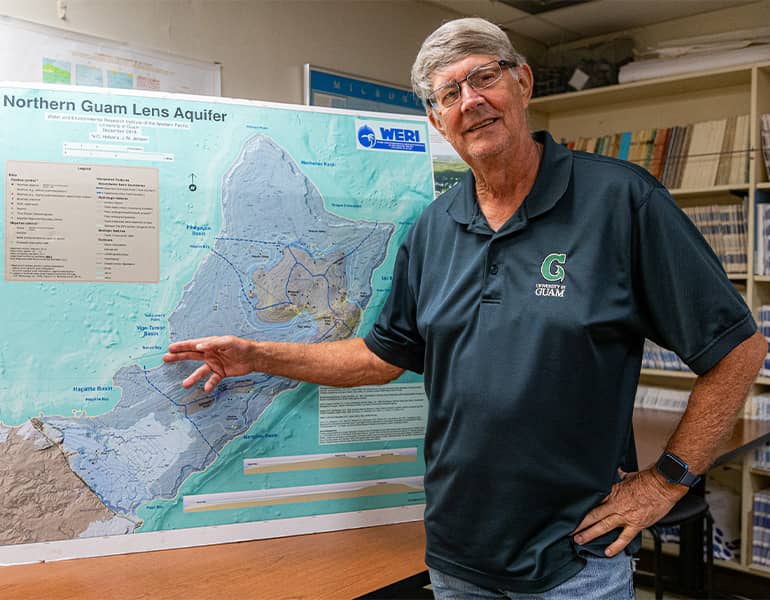 Dr. Ross Miller poses in front of Northern Guam Lens Aquifer Map