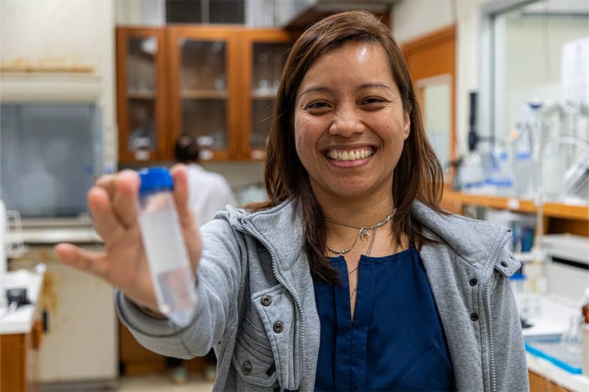 Mallary Duenas holds out test tube at Water and Environmental Research Institute of the Western Pacific