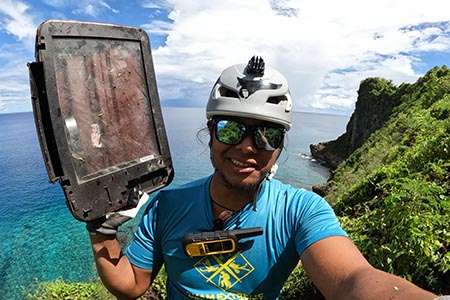 Farron Taijeron takes a video of himself picking up dumped electronics at Oka Point.