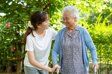 Social worker woman helps elderly woman walk.