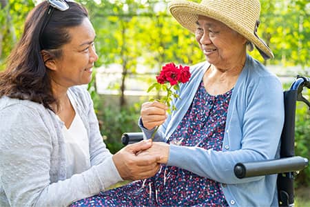 A caregiver helps an elderly woman in a wheelchair