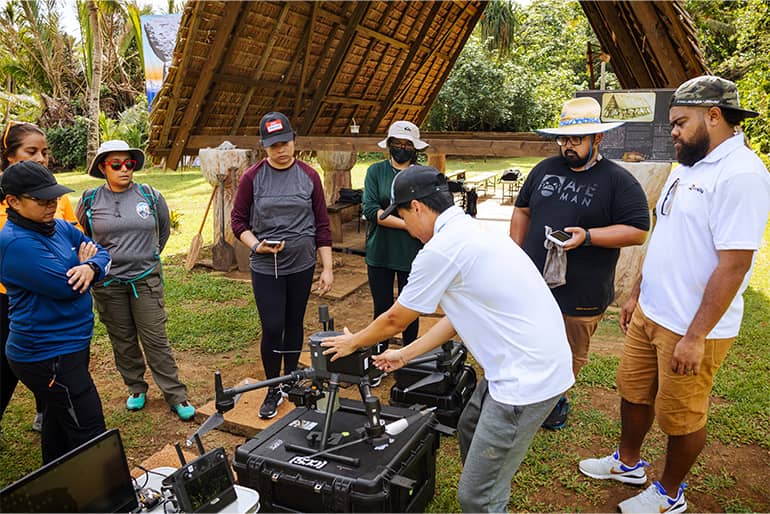 Members of UOG Drone Corps program observe Dong Won Lee as he demonstrates how to properly prepare a drone for flight during mission