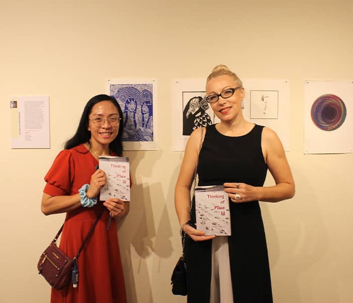 Joleen Unas poses with art professor Dr. Irena Keckes in front of wall display featuring her artwork “Amabie”