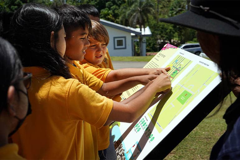 Young children point to map near their school and Talo’fo’fo Baseball Field.