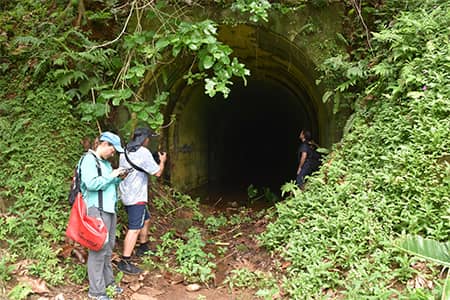 Team members who surveyed wartime relics stand at WWII bunker entrance