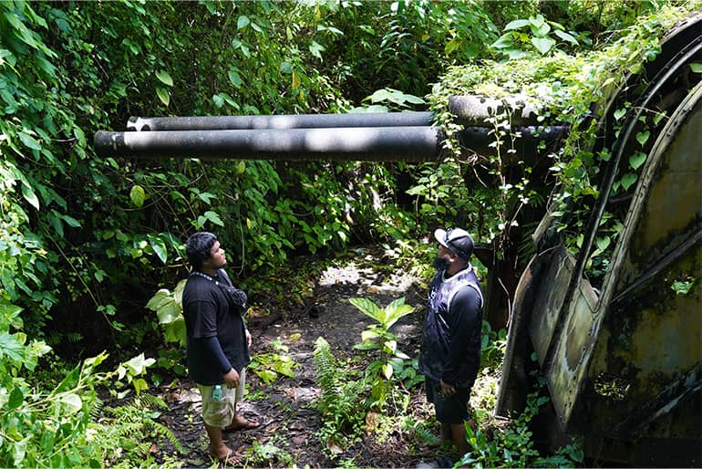Chuuk Historic Preservation Officer and Technical Assistant observe anti-aircraft gun