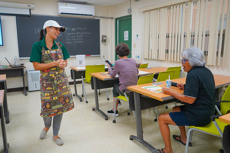 woman in apron teaching a cooking class in an univeristy classroom