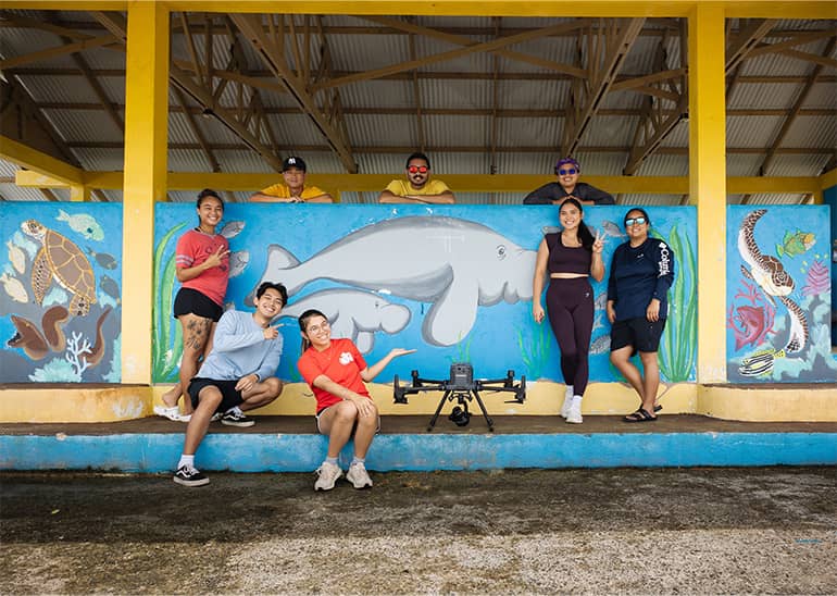 UOG staff and students pose for a photo in front of sea mural after sample fluid lensing mission.