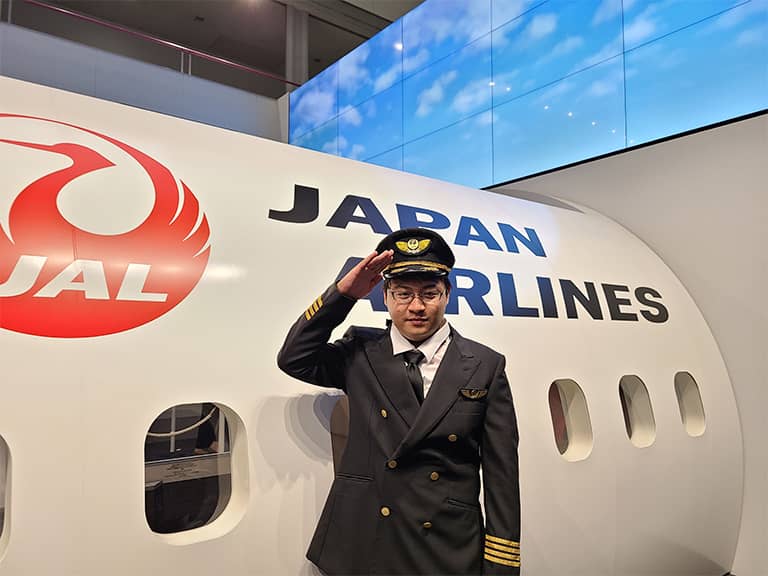 Raiki Ueda Leon Guerrero poses for a photo, saluting and wearing a JAL pilot uniform, at JAL’s Sky Museum in Tokyo.