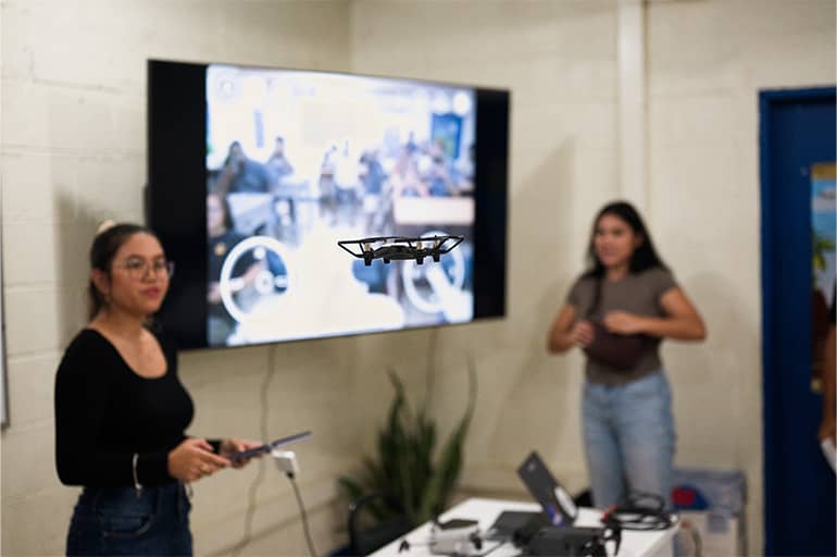 UOG Drone Corps outreach coordinator and UOG environmental science graduate student demonstrate drone in mid-flight to students in Palau.