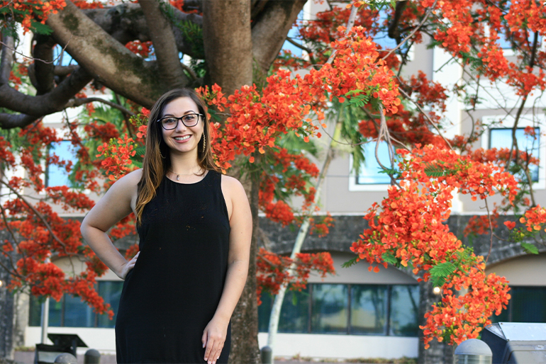 Arielle Lowe poses for photo in front of flame tree