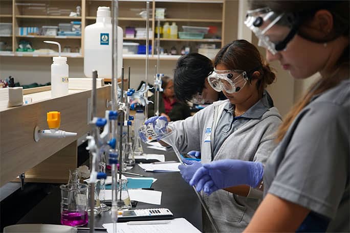 Zoe Leung pours liquid into container during UOG Chemistry Titration Competition