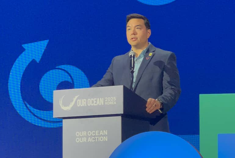 Austin Shelton speaks at podium on colorfully lit stage