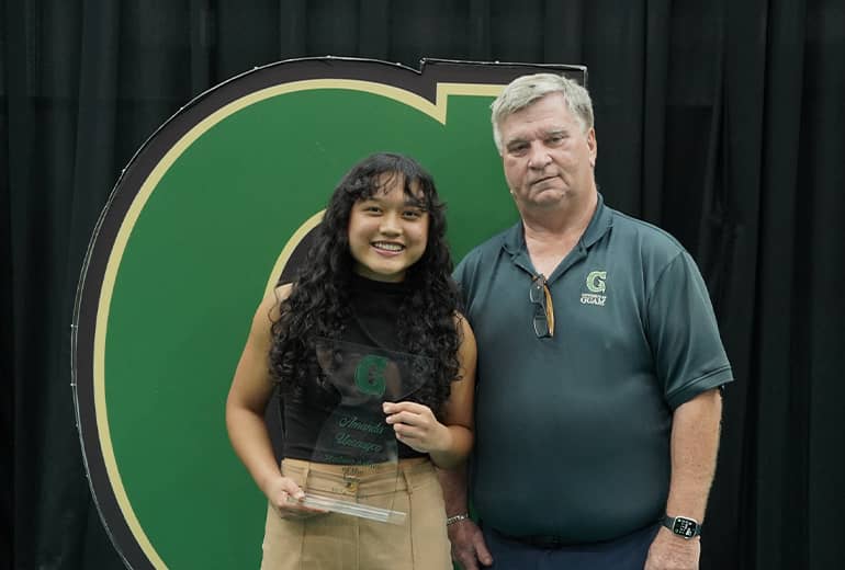 Amanda Uncangco and Doug Palmer pose for photo with trophy and Triton G sign