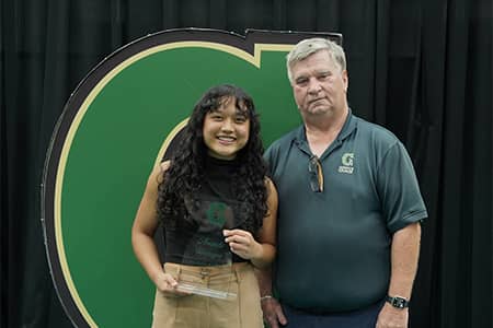 Amanda Uncangco and Doug Palmer pose for photo with trophy and Triton G sign
