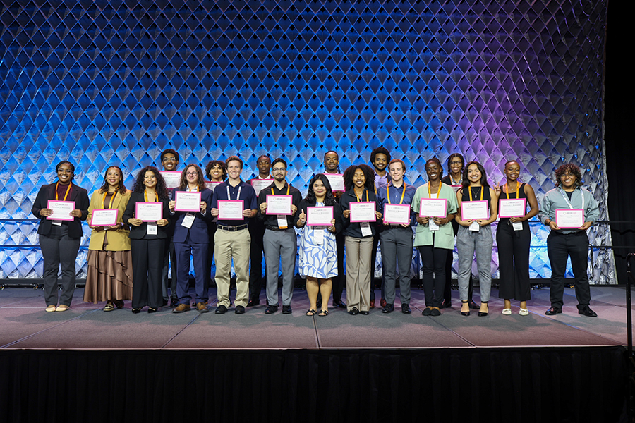 UOG biology major Danielle Balmores holds an award certificate among the other student awardees at the ABRCMS Conference in the subject area of engineering, physics, and mathematics. A group of students on stage holding award certificates