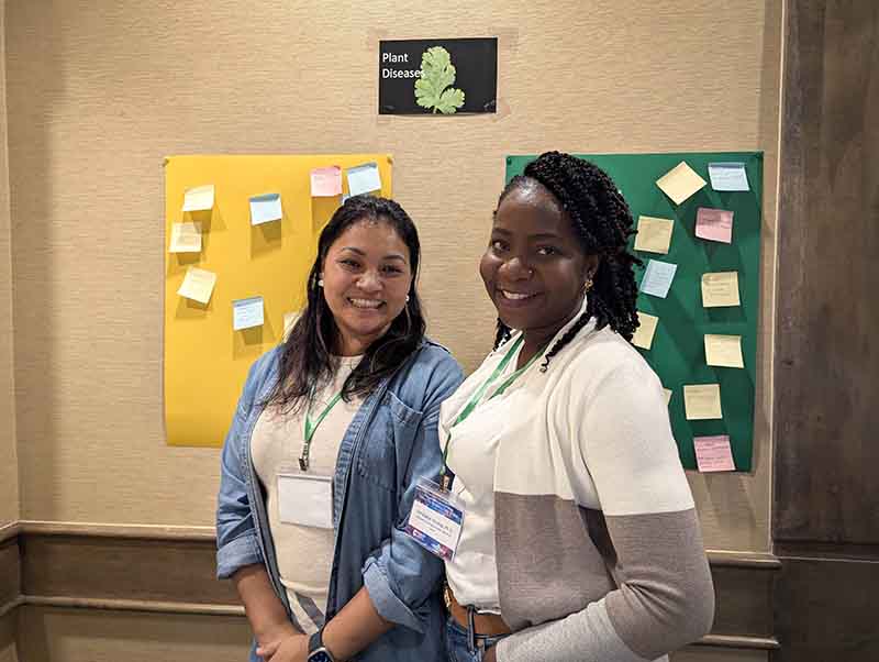 Bindu Poudel-Ward, left, and Christianah Oladoye, the new extension plant pathologist and soil researcher with University of Guam Land Grant, respectively. During a session of the 2025 Guam Farmer Focus Conference on Oct. 29, 2025, they asked participants to submit sticky notes with what they considered to be the most pressing threats and pests to the island’s crops. Two women standing in front of a wall of sticky notes