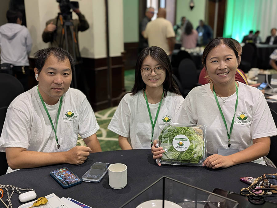 Three people holding a packaged lettuce product