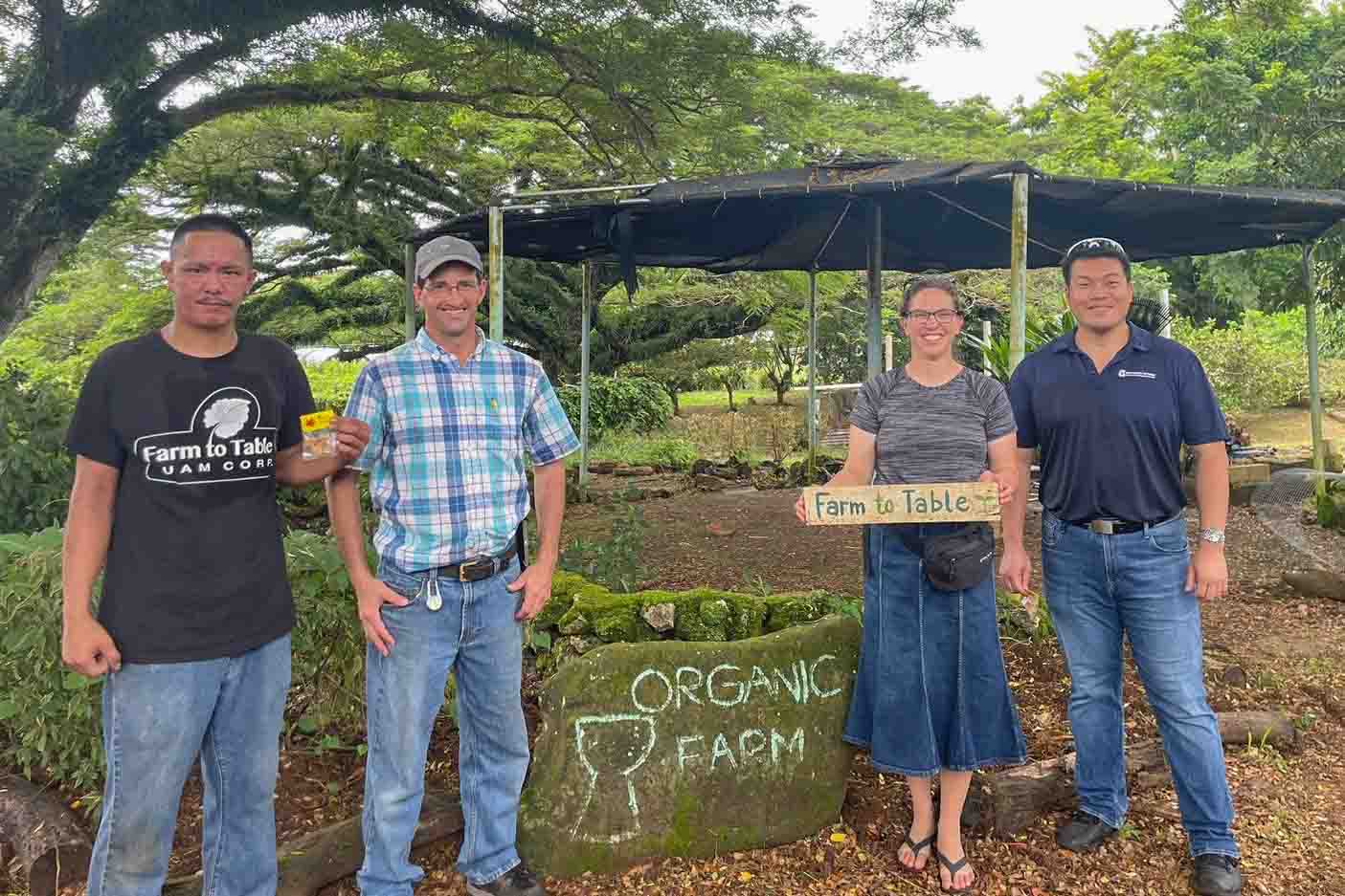 Four people standing on a Guam farm